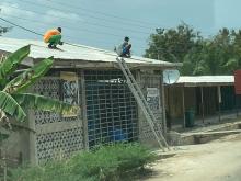 Moses and Ayoo are up on the roof of the Dekpor Central Shops, putting in roofing nails