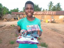 Sponsored tailor apprentice, Kwasi, smiles as he holds his undershirts, boxers, and socks