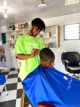 Barber, Obed, is inside the salon working on the hair of a male customer