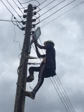 electrician has climbed to the top of an electrical post and is installing a new street light