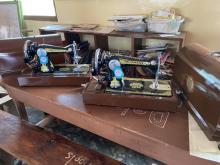 2 black hand crank sewing machines sitting on a table