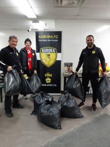 3 Aurora FC representatives show off the bags of donated soccer clothes