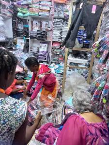 Linda in the forefront, other women are sorting through bags of undergarments in a market shop
