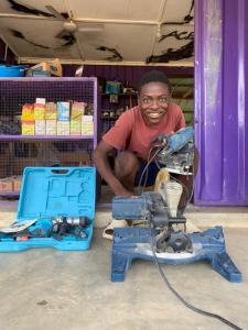 a man with big smile crouches behind his new saw