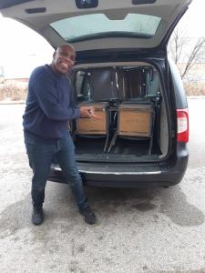 Man stands in front of van full of stacking chairs