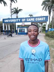 Albert stands in the foreground with the University of Cape Coast sign behind him